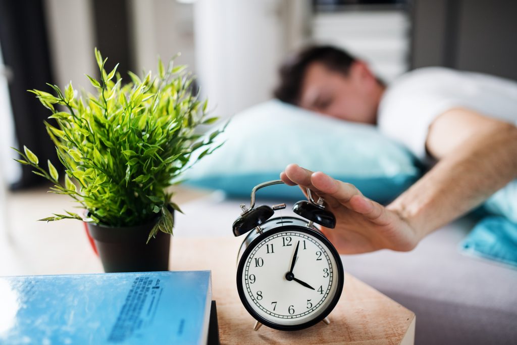 young tired man hitting alarm clock in bed at home 2021 08 27 16 33 54 utc